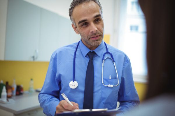 Doctor interacting with patient and writing on clipboard Doctor interacting with patient and writing on clipboard