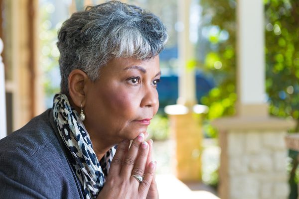 Mature woman in deep thought or prayer on front porch Mature woman in deep thought or prayer on front porch