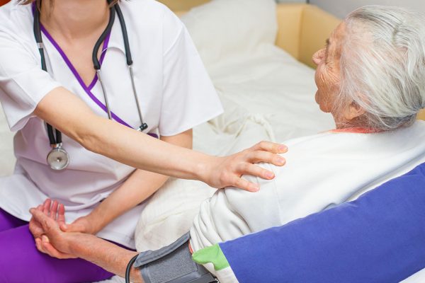 young nurse caregiving an old lady lying in bed young nurse caregiving an old lady lying in bed