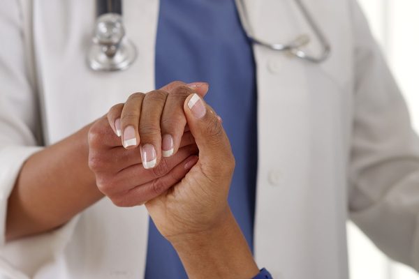Close up of female African American doctor holding patient’s hand Close up of female African American doctor holding patient's hand
